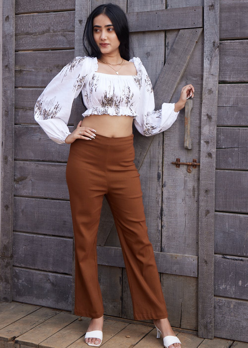 a classic workwear with wide leg brown trousers and black full sleeved  tshirt with a belt, holding a bag in hand - Theunstitchd Women's Fashion  Blog